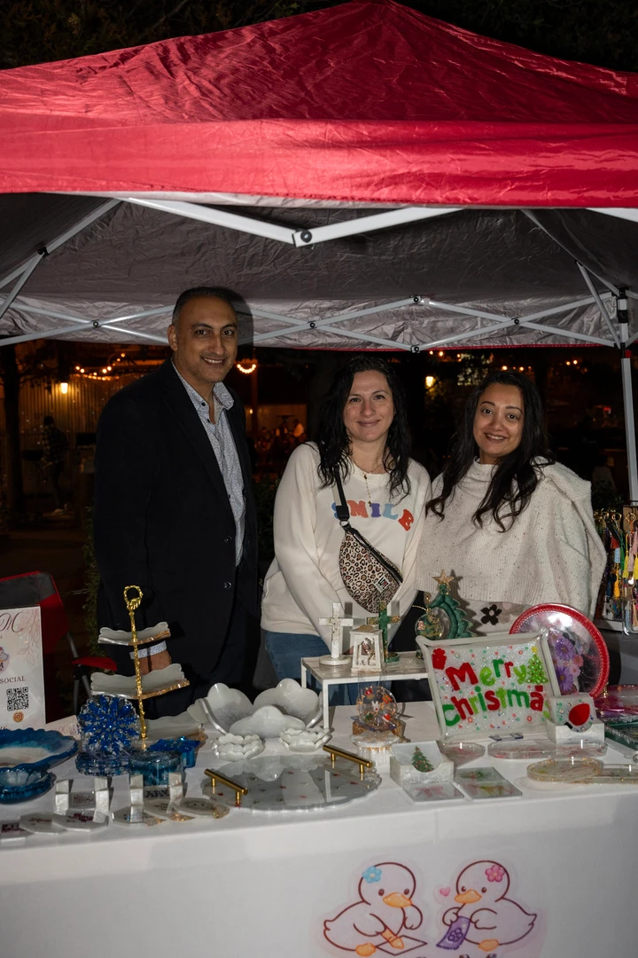 Three smiling makers behind a holiday gift display.