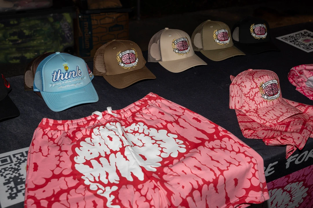 Printed shirts and hats displayed at an outdoor stall.