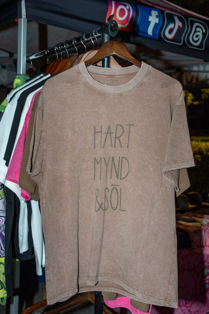 Printed shirts and hats displayed at an outdoor stall.