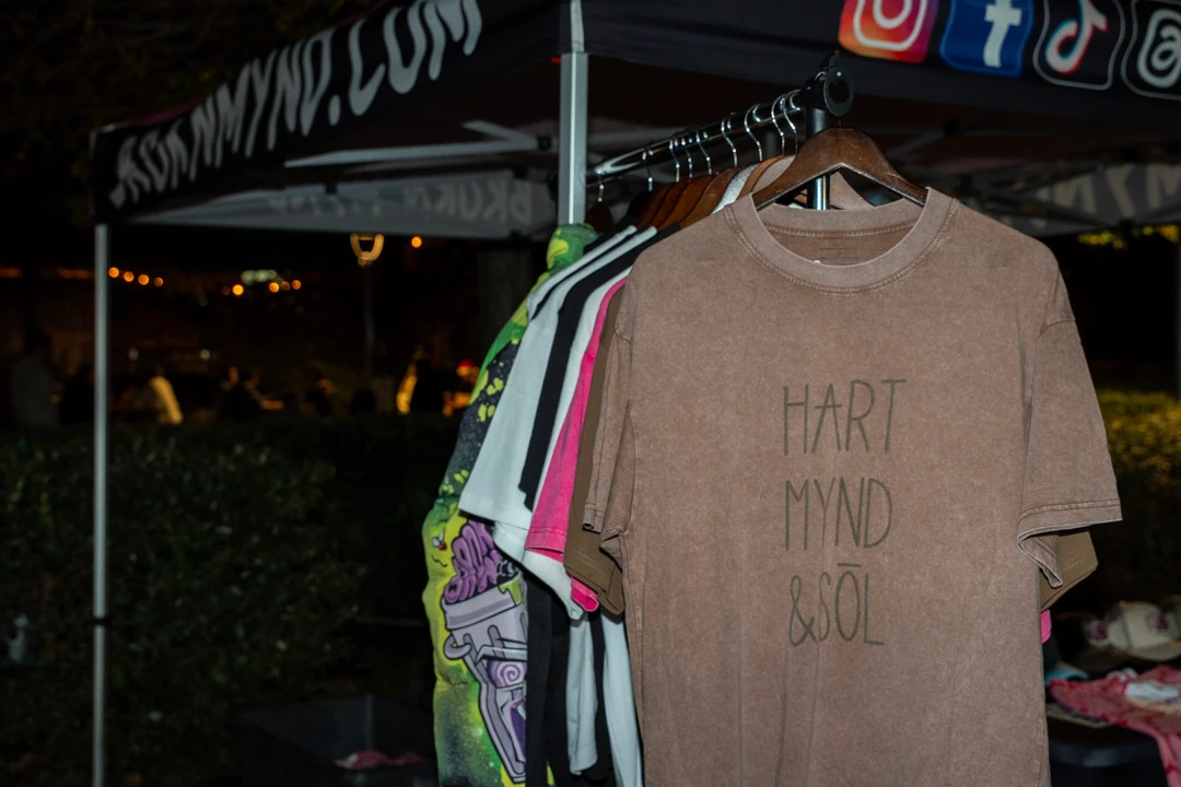 Printed shirts and hats displayed at an outdoor stall.