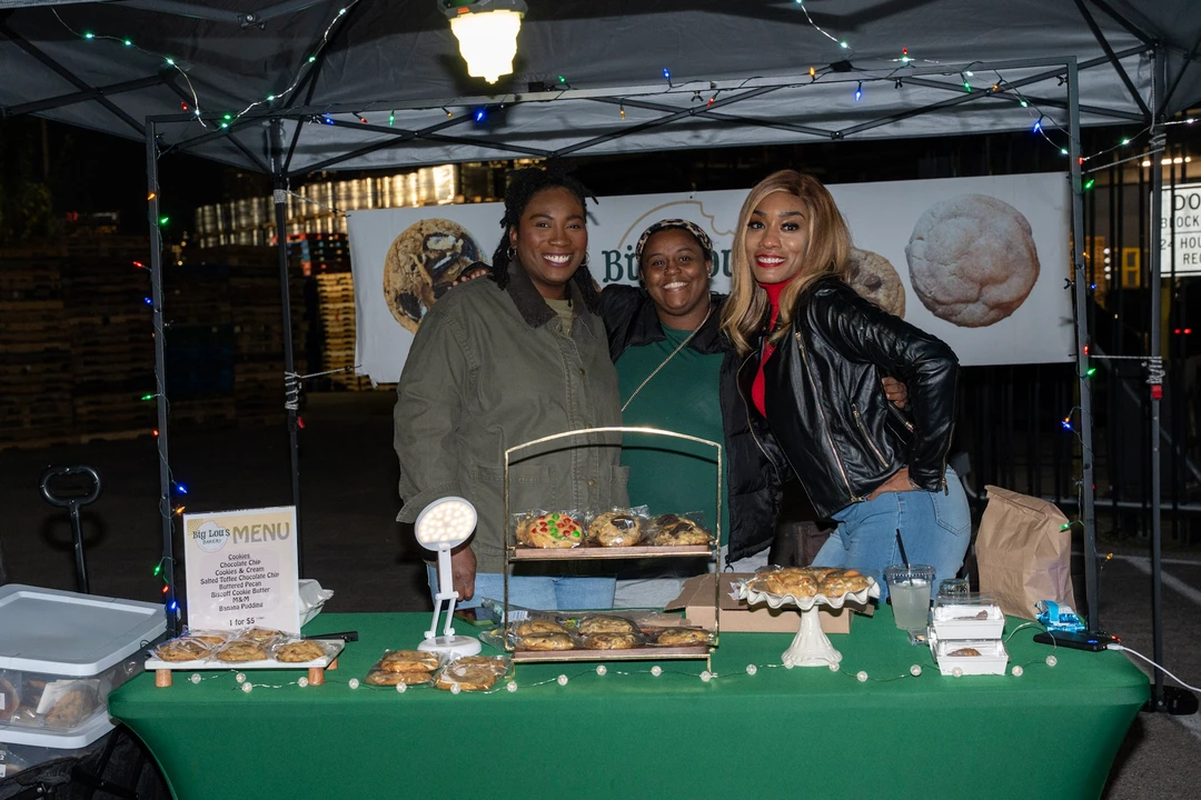 Three makers behind a green-covered baked-goods table.