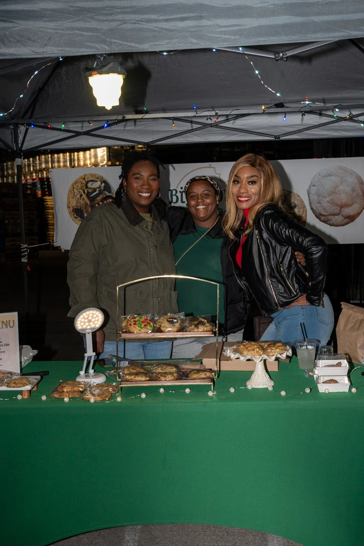Three makers behind a green-covered baked-goods table.