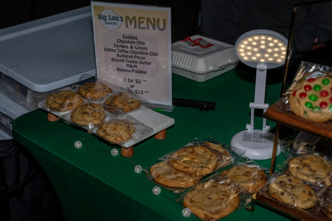 Decorated cookies displayed in trays on a green-covered table.