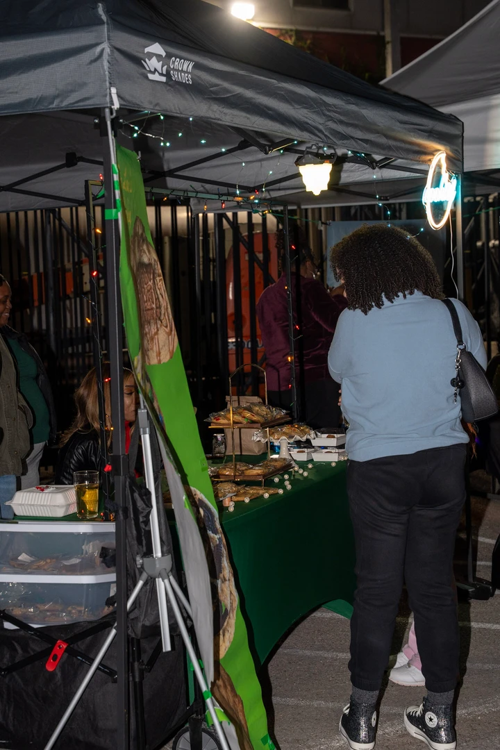 Shoppers browsing a cookie stall beneath evening lights.