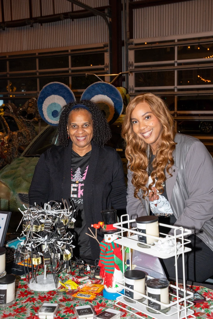 Two makers behind a jewelry and accessory display.