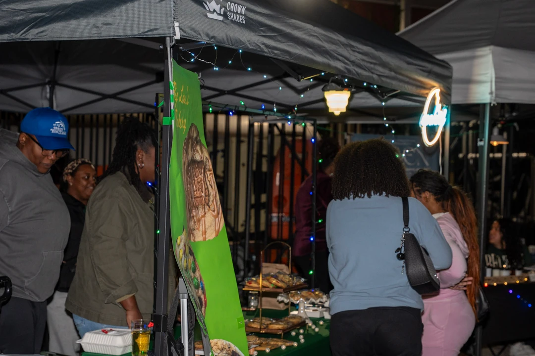 Shoppers browsing a cookie stall beneath evening lights.