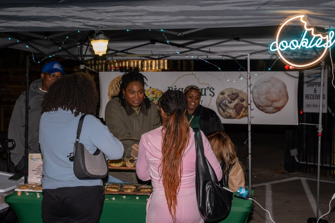 Shoppers browsing a cookie stall beneath evening lights.