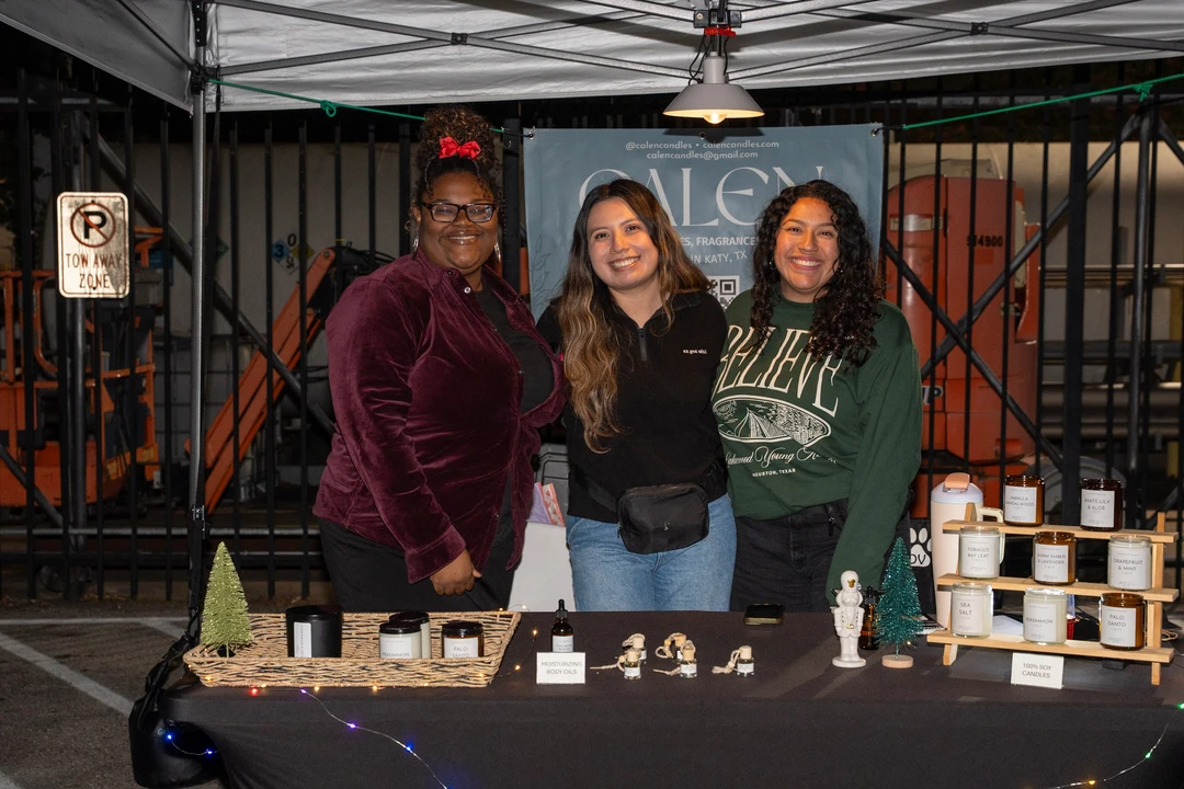Three smiling makers behind a candle display.