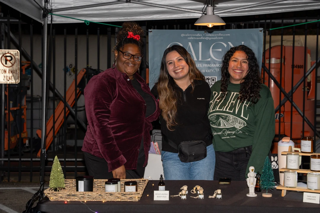 Three smiling makers behind a candle display.
