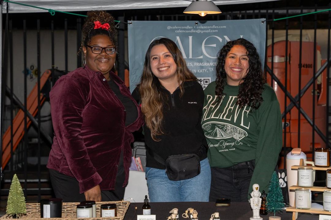 Three smiling makers behind a candle display.