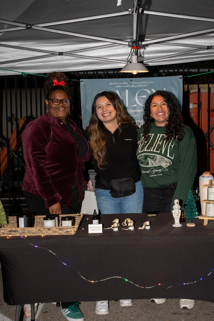 Three smiling makers behind a candle display.