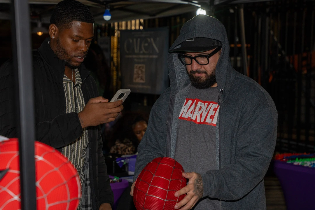 Two visitors examining a red superhero-themed bag.