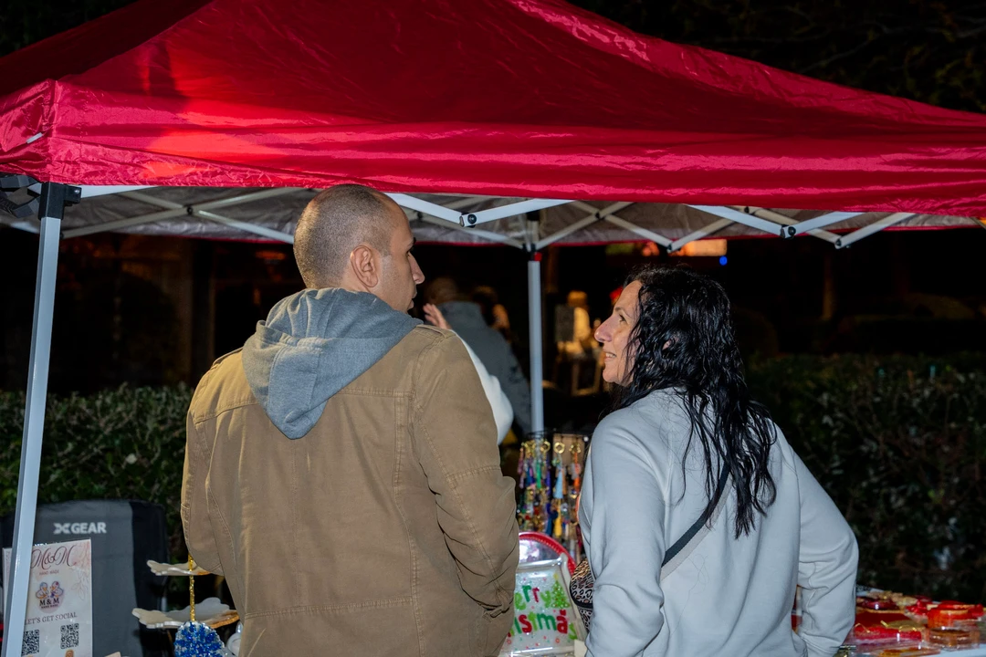 Shoppers gathering at a stall beneath a red canopy.