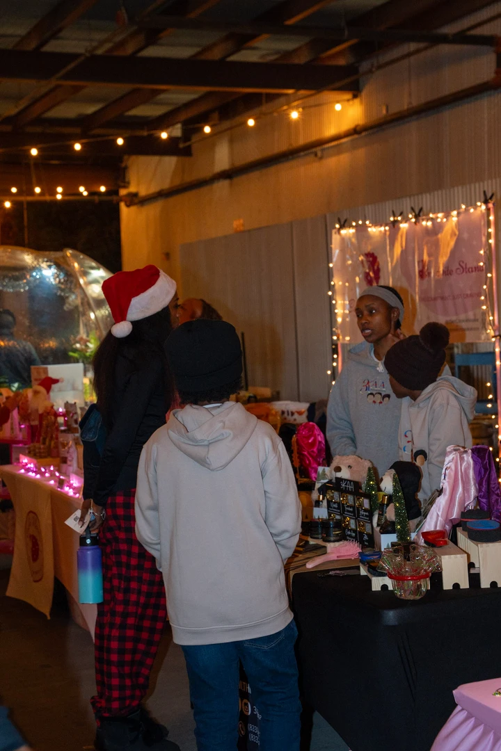 Shoppers at an illuminated indoor holiday stall.