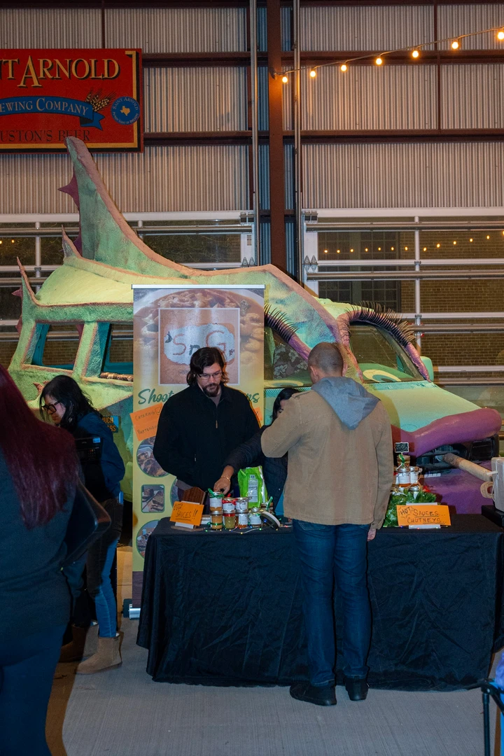 Makers and visitors at colorful indoor market stalls.