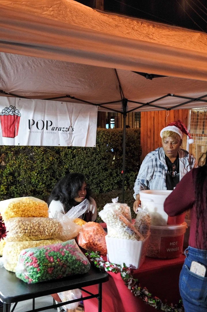 Visitors browsing a table of colorful handmade goods.