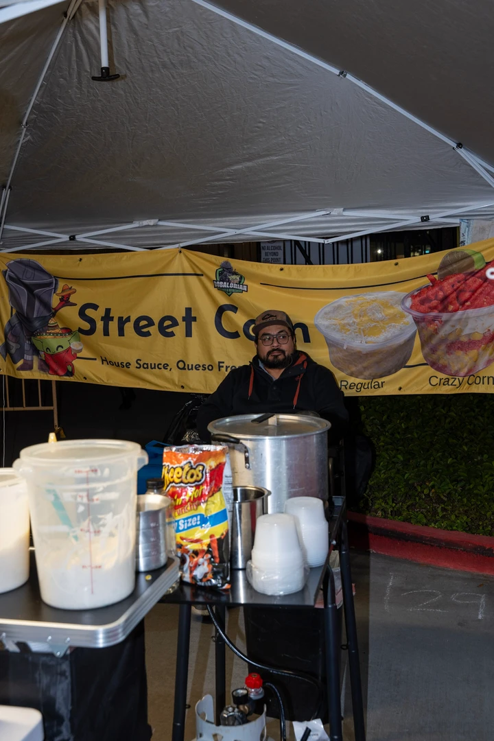 A food vendor standing beneath a Street Corn banner.
