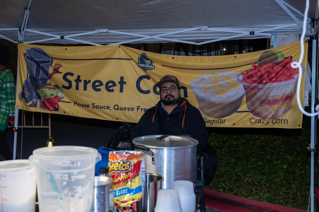 A food vendor standing beneath a Street Corn banner.