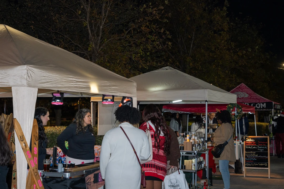 Visitors at an outdoor stall beneath a white canopy.