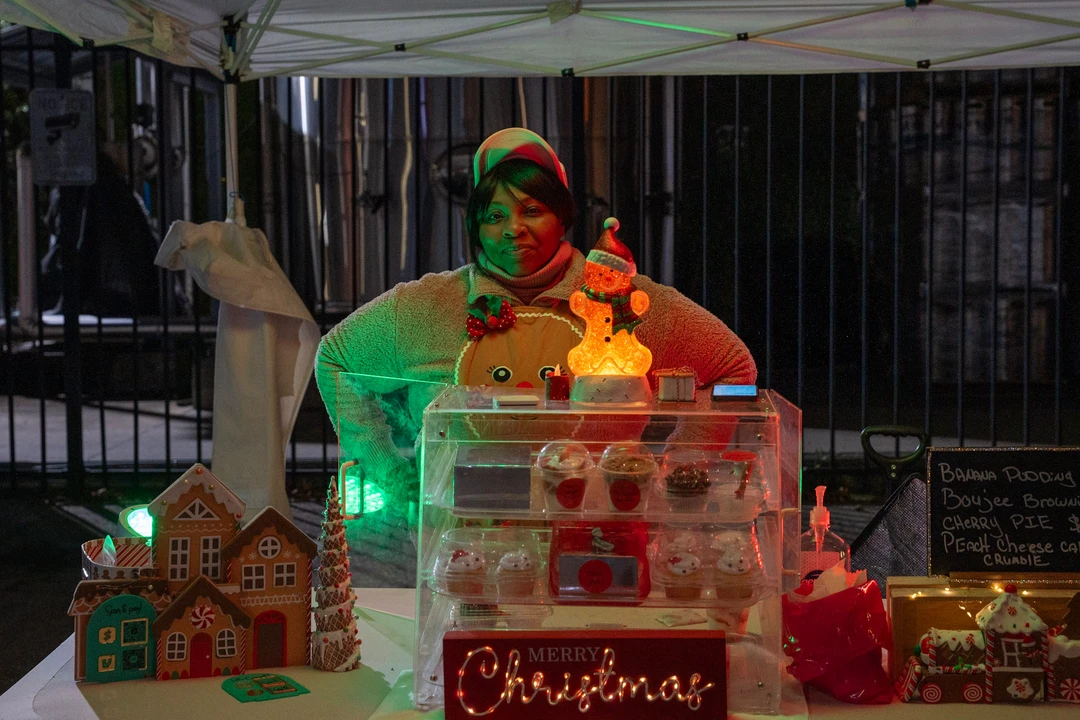 A festively dressed vendor behind a colorful holiday display.