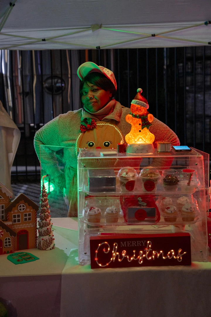 A festively dressed vendor behind a colorful holiday display.