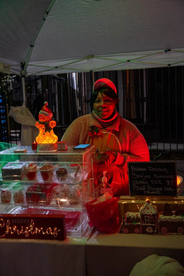 A festively dressed vendor behind a colorful holiday display.