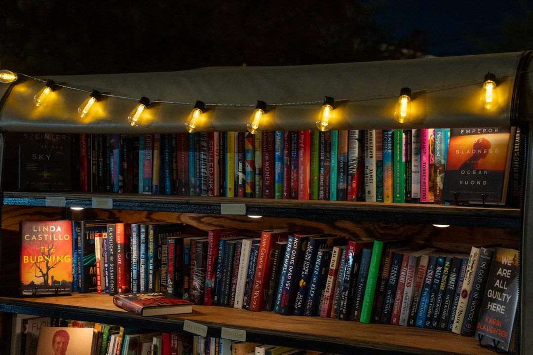 Rows of colorful books on the illuminated shelves of a mobile bookshop.