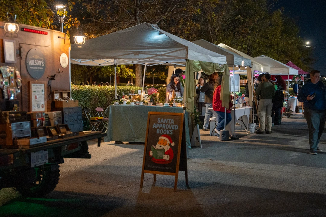 Outdoor market tents and a bookshop menu board at night.