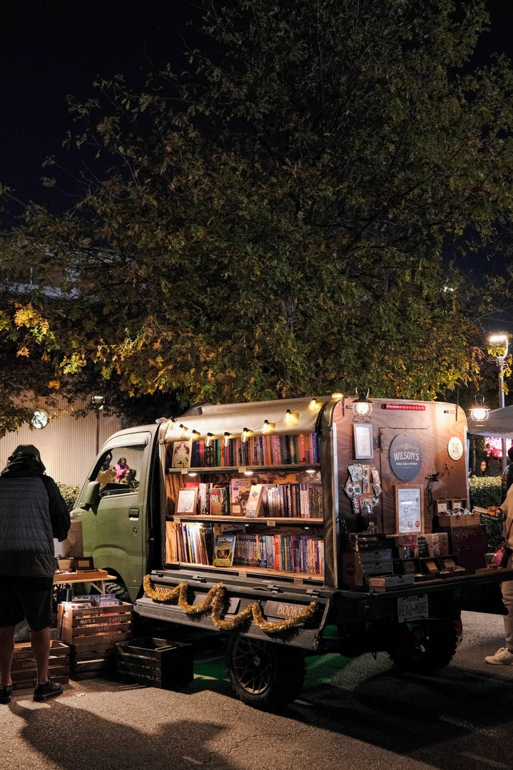 An illuminated mobile bookshop beside the night market.