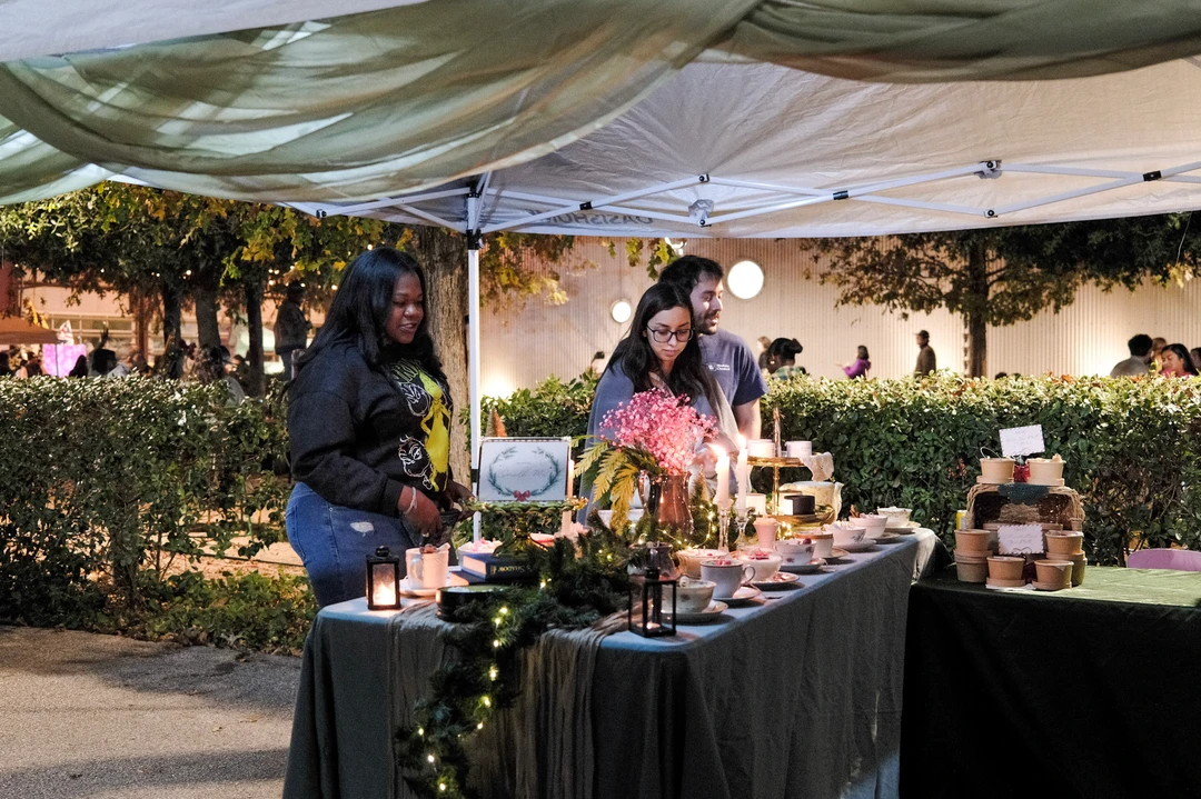 A maker arranging flowers and greenery at her night-market stall.