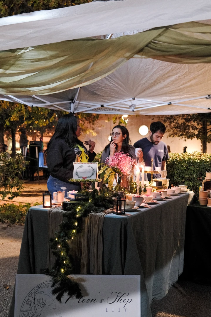 A maker arranging flowers and greenery at her night-market stall.