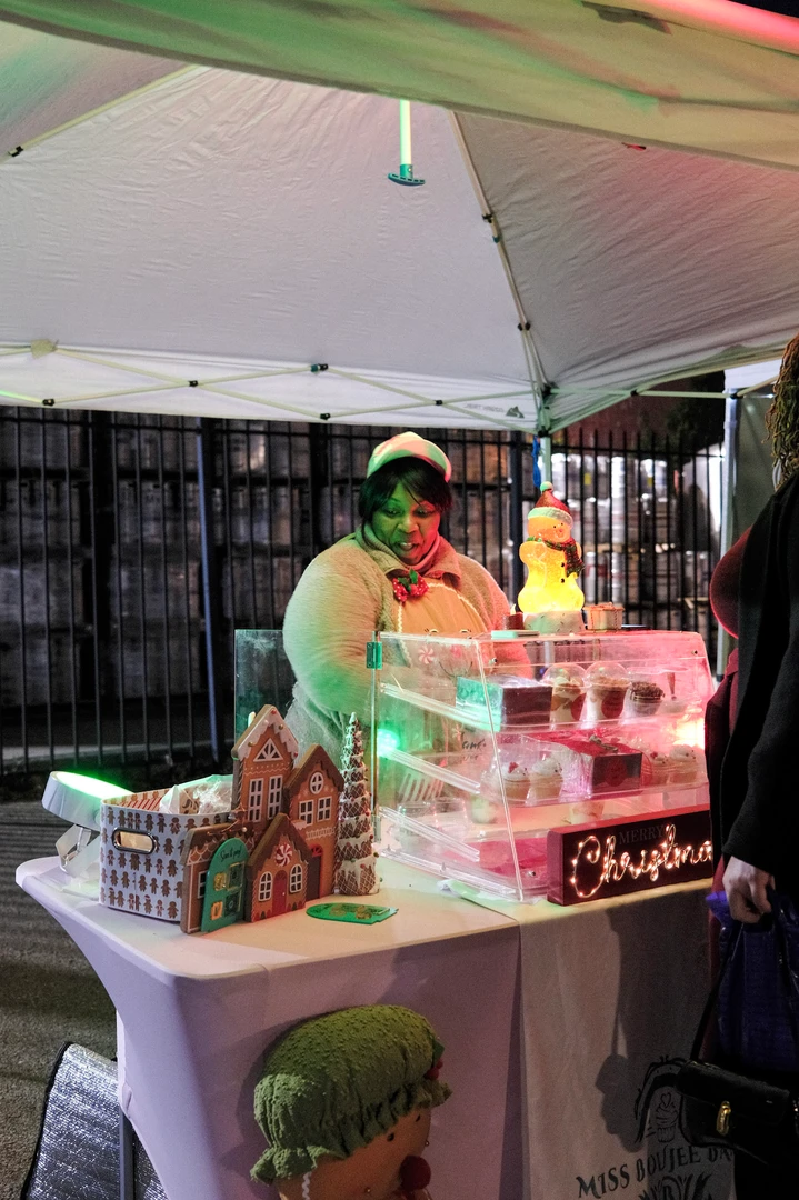 A festive vendor behind a pink display beneath a white canopy.