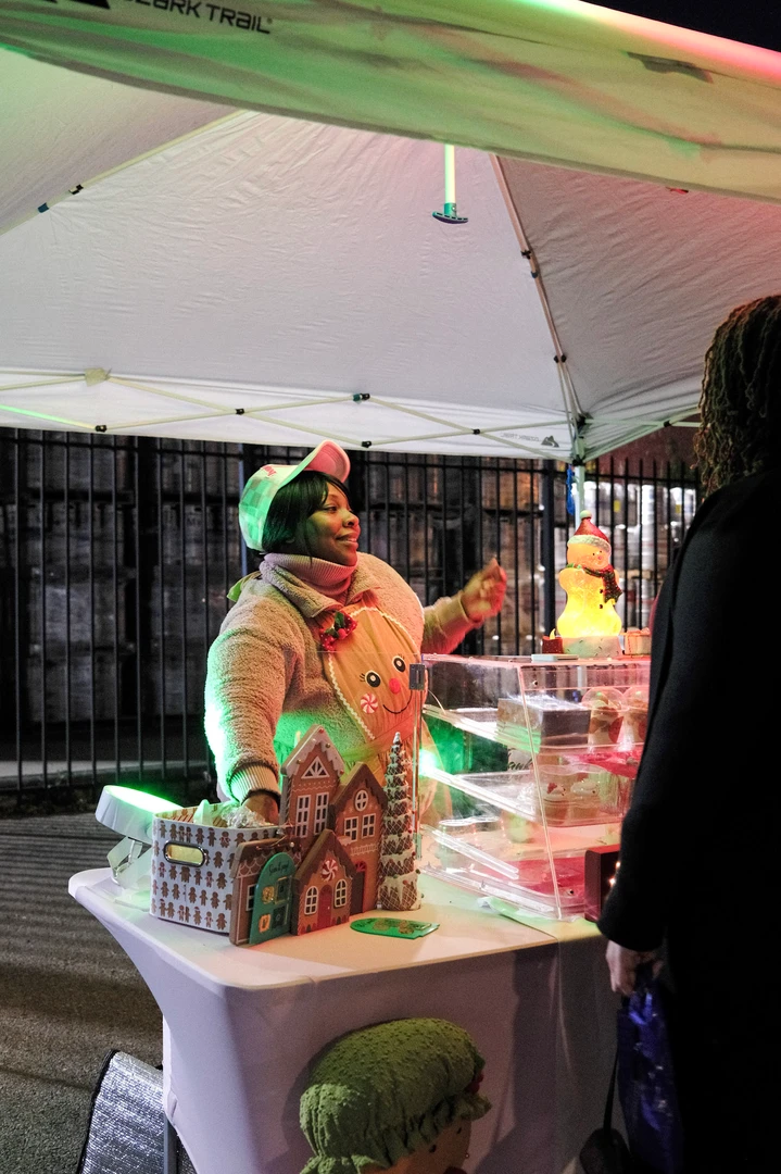 A festive vendor behind a pink display beneath a white canopy.