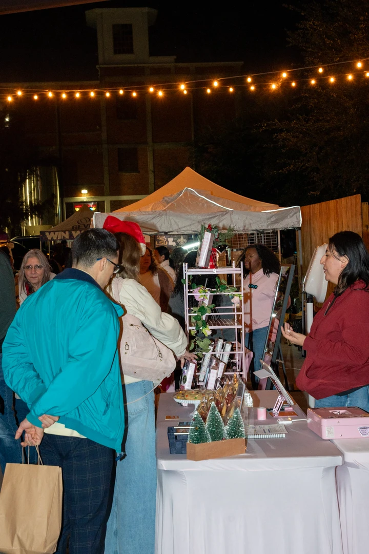 Shoppers browsing stalls beneath warm evening lights.