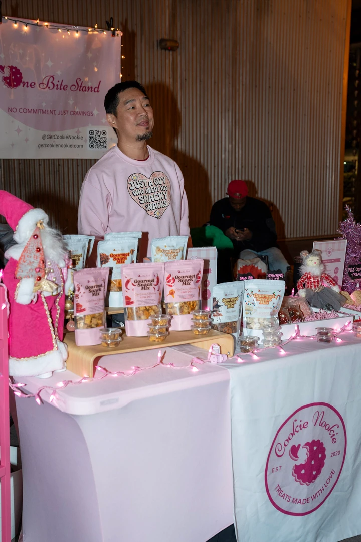 A maker in pink standing behind her holiday display.