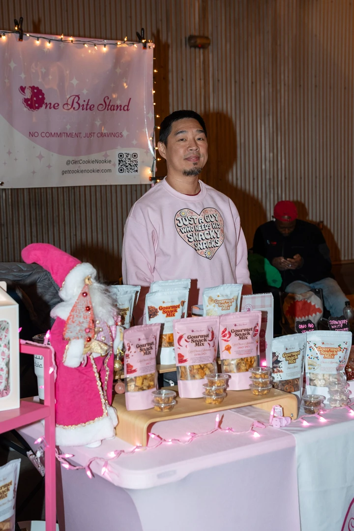 A maker in pink standing behind her holiday display.