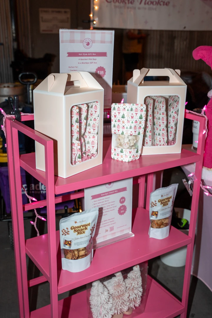 Pink holiday gifts and festive containers on a market display.