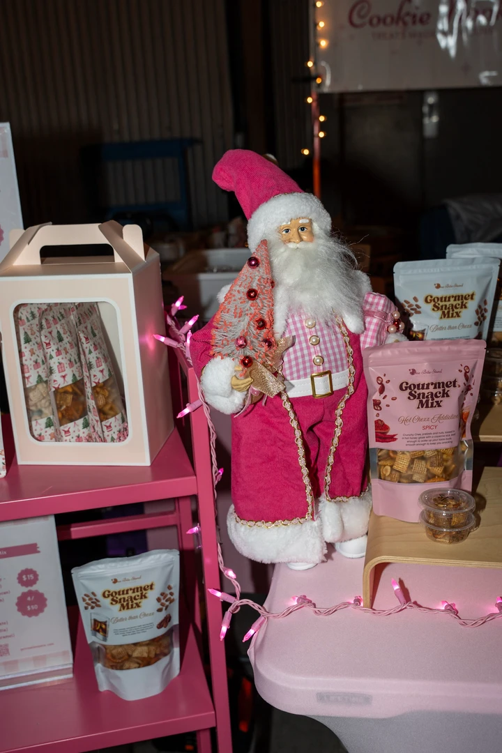 Pink holiday gifts and festive containers on a market display.