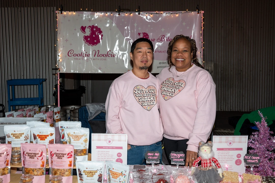 Two smiling makers in pink stand behind their holiday display.