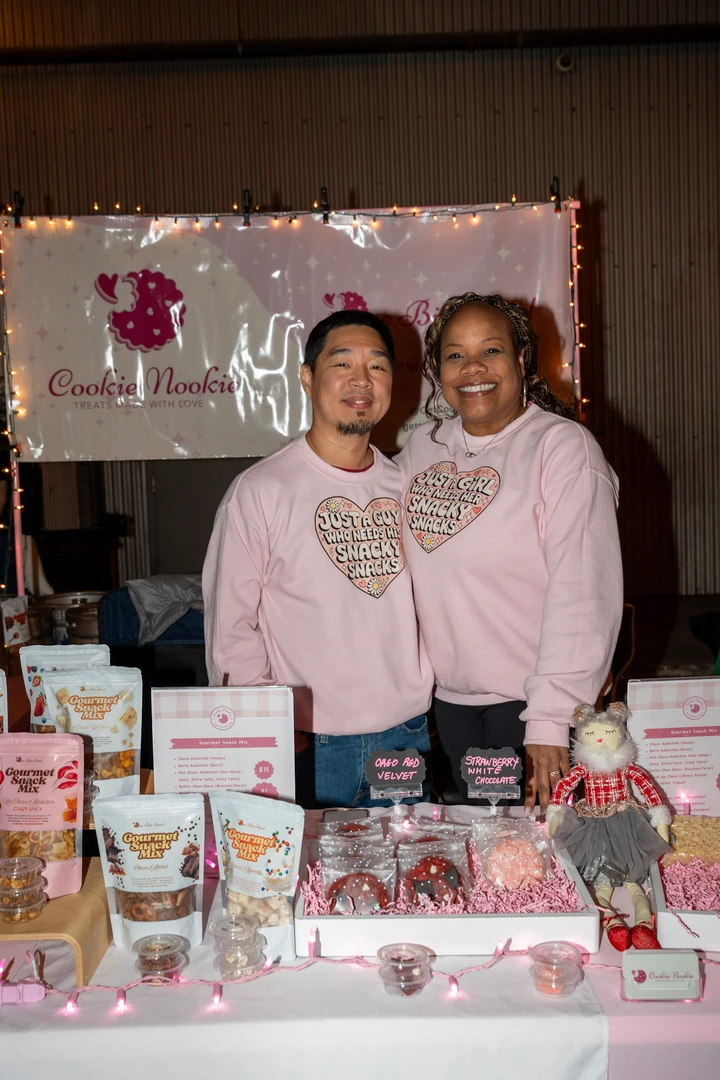 Two smiling makers in pink behind their holiday display.