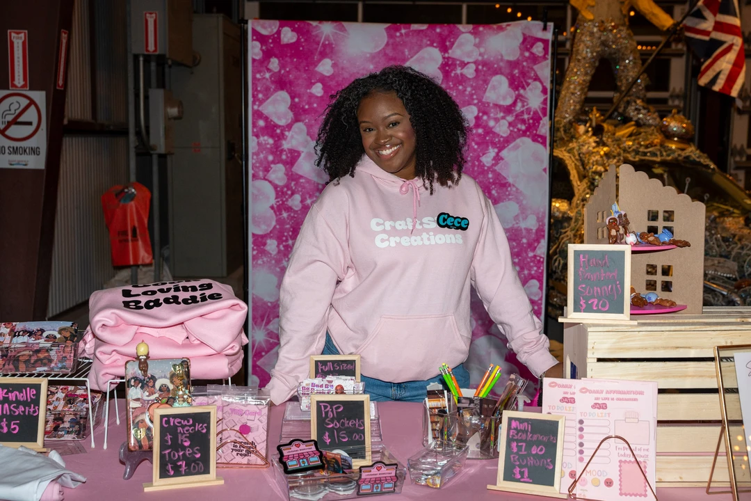 A maker in pink behind the Craftzy Creations holiday stall.