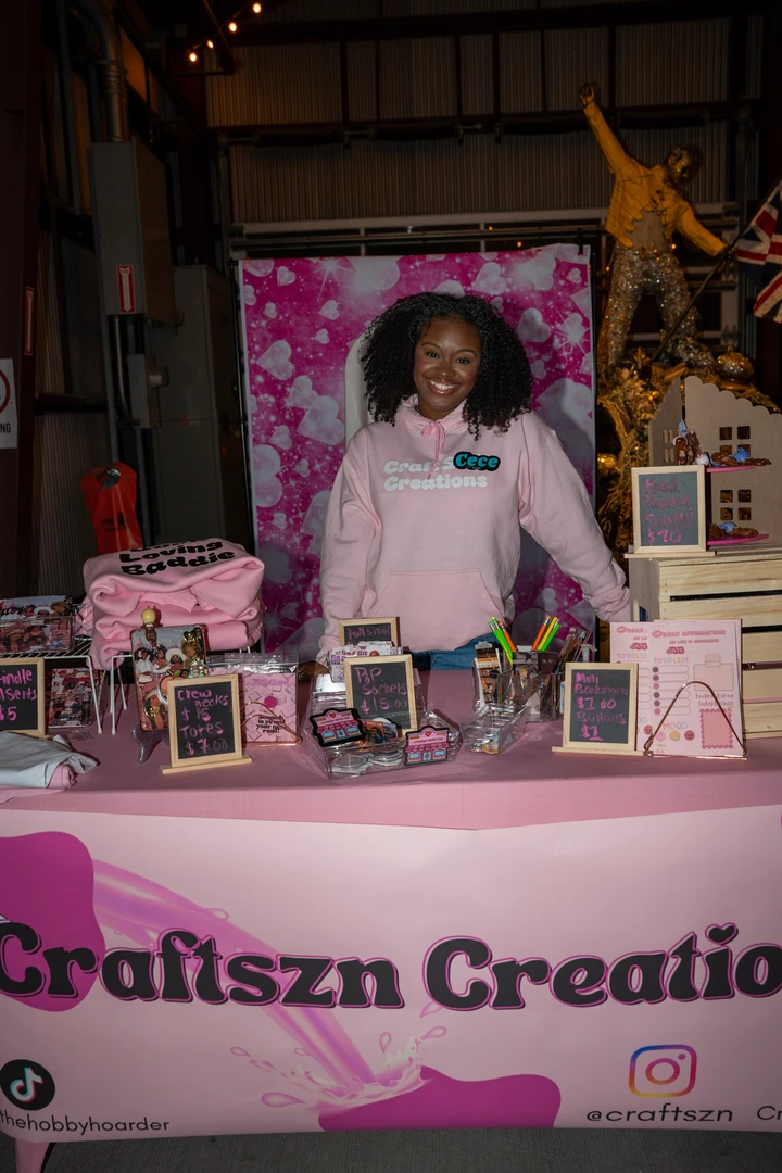 A maker in pink behind the Craftzy Creations holiday stall.