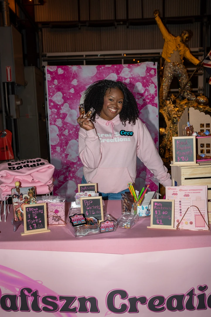 A maker in pink behind the Craftzy Creations holiday stall.