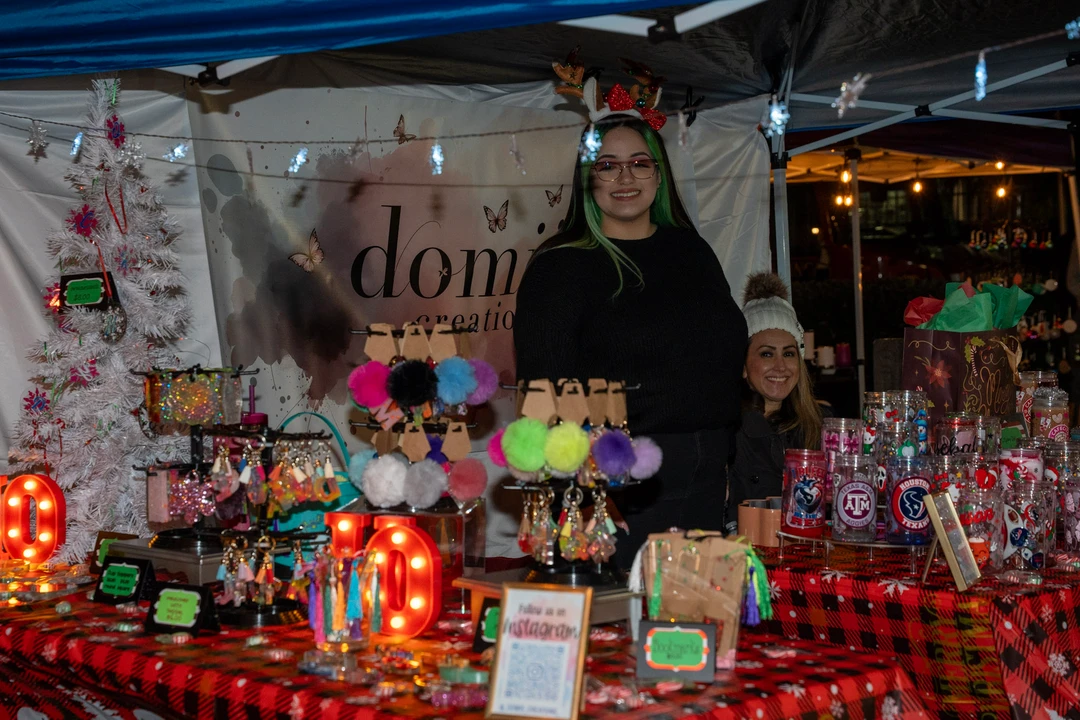 Two makers standing behind a crocheted flower display.
