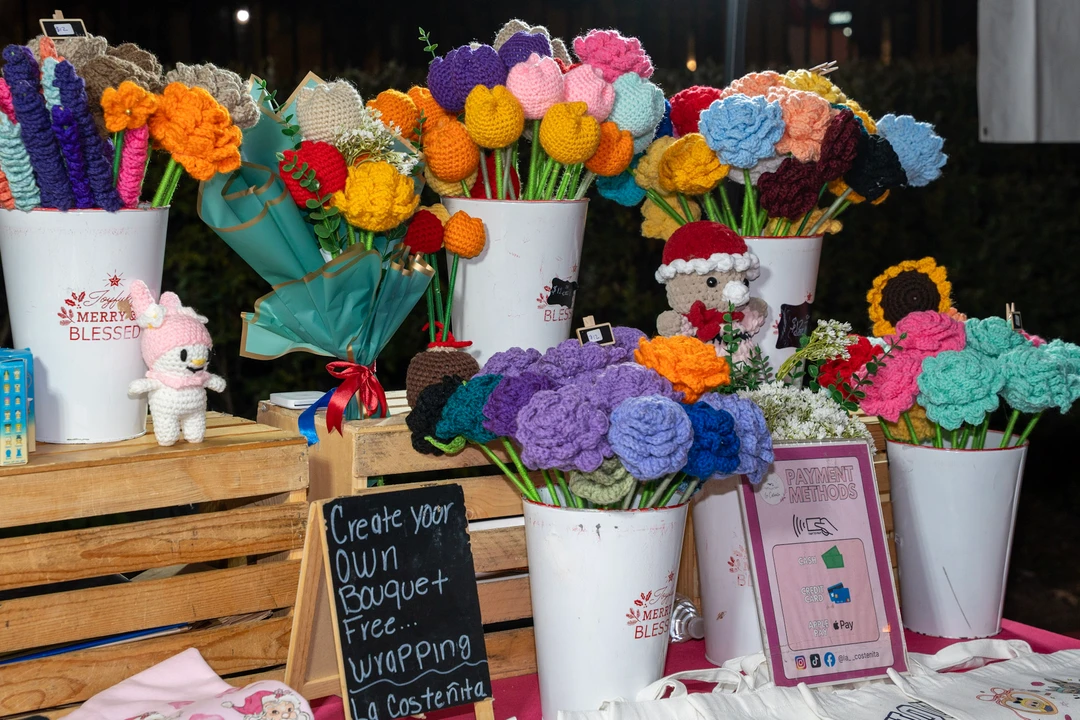 Crocheted flowers in colorful bouquets at a holiday market stall.