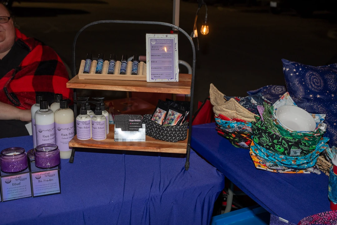 Handmade soap and small packaged goods on a purple tablecloth.