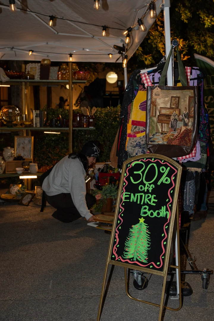A chalkboard sign and greenery beside the night market.
