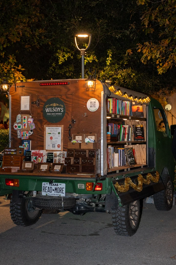 Visitors and shelves of books at the illuminated mobile bookshop.