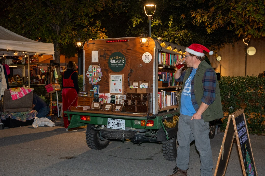 Visitors and shelves of books at the illuminated mobile bookshop.