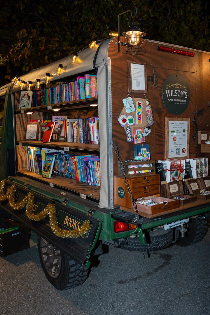 Visitors and shelves of books at the illuminated mobile bookshop.